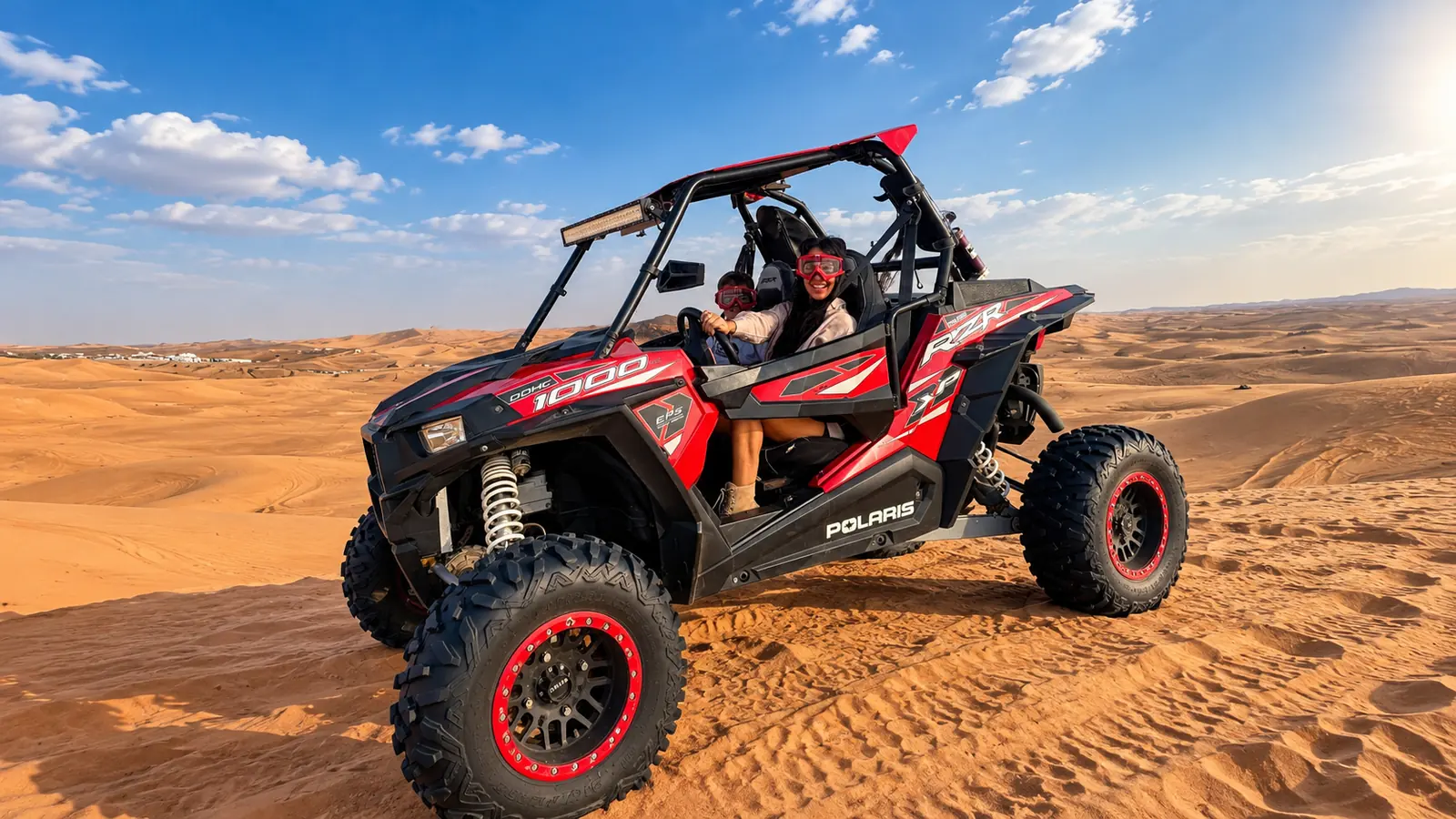 Red Polaris RZR 1000 dune buggy on Abu Dhabi desert dunes at golden hour