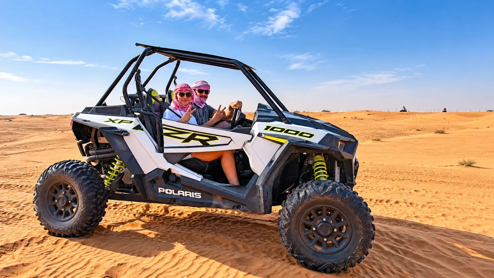 Couple driving a white Polaris RZR XP 1000 two-seater dune buggy in the Abu Dhabi desert