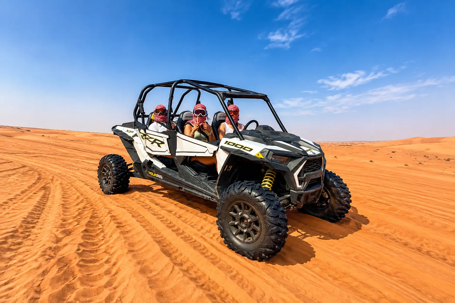 Group of three riders in a Polaris RZR 4-seater dune buggy on Abu Dhabi dunes